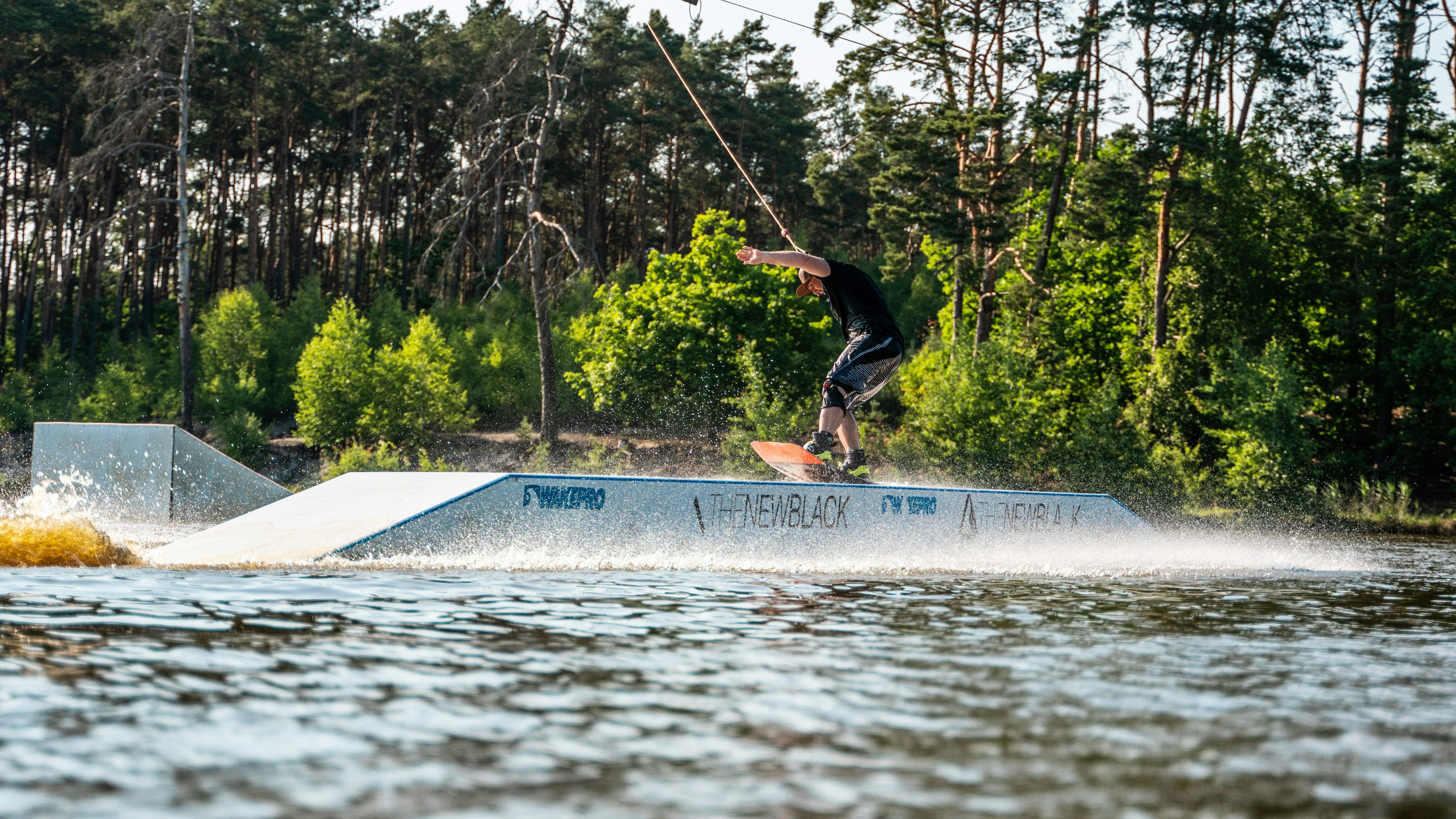 man in black jacket and black pants riding on blue skateboard during daytime