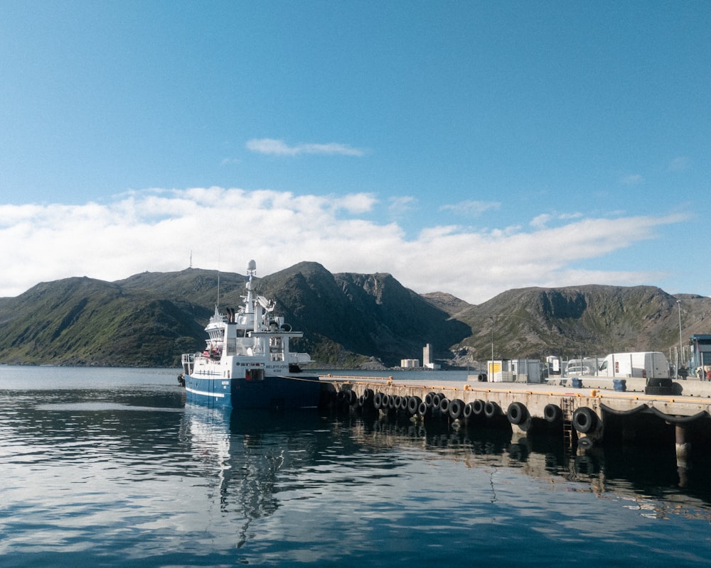 white and blue ship on sea near mountain under blue sky during daytime