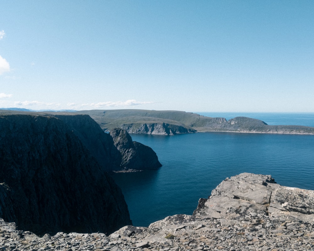 Montaña rocosa marrón junto al mar azul bajo el cielo azul durante el día