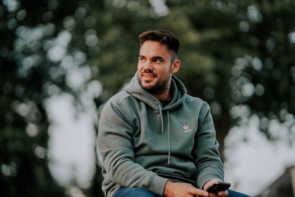 man in gray hoodie holding black dslr camera