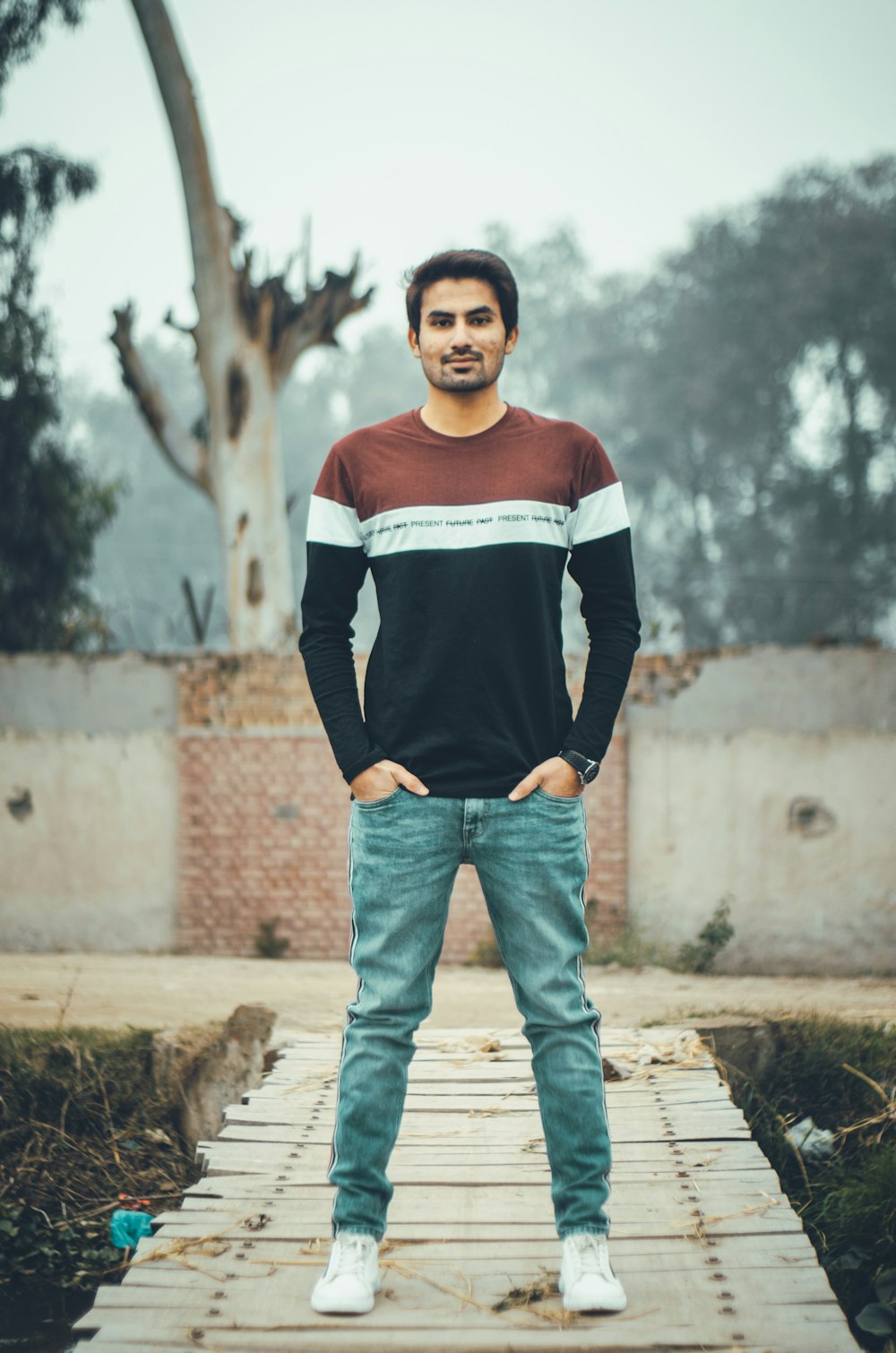 boy in black and white long sleeve shirt and blue denim jeans standing on brown concrete