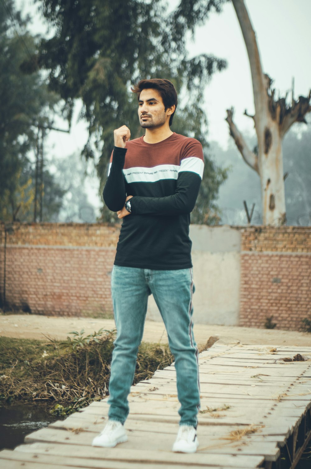 woman in white and black long sleeve shirt and blue denim jeans standing on brown soil