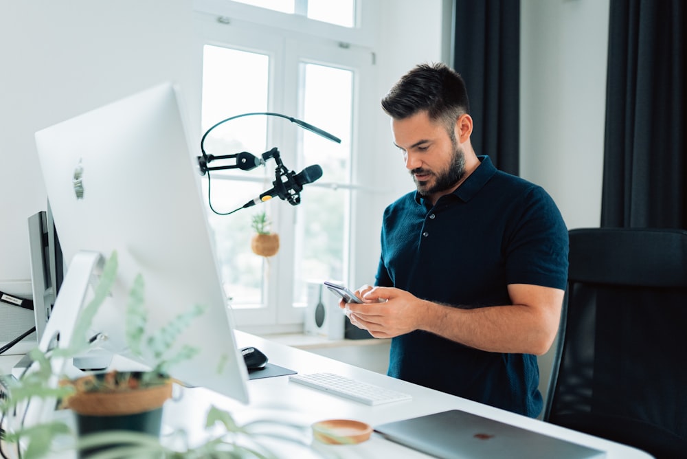 homem na camisa polo azul segurando ipad prateado