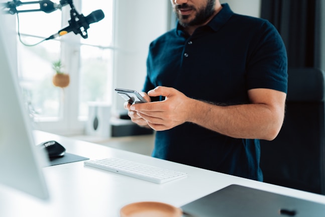 A person happily answering questions on a smartphone at a cozy home desk.
