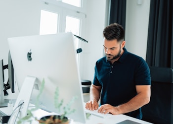 man in blue polo shirt using laptop computer