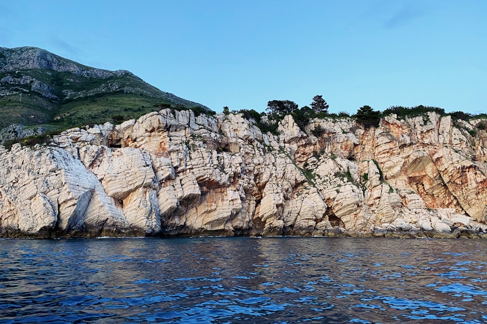 brown rock formation beside blue sea under blue sky during daytime