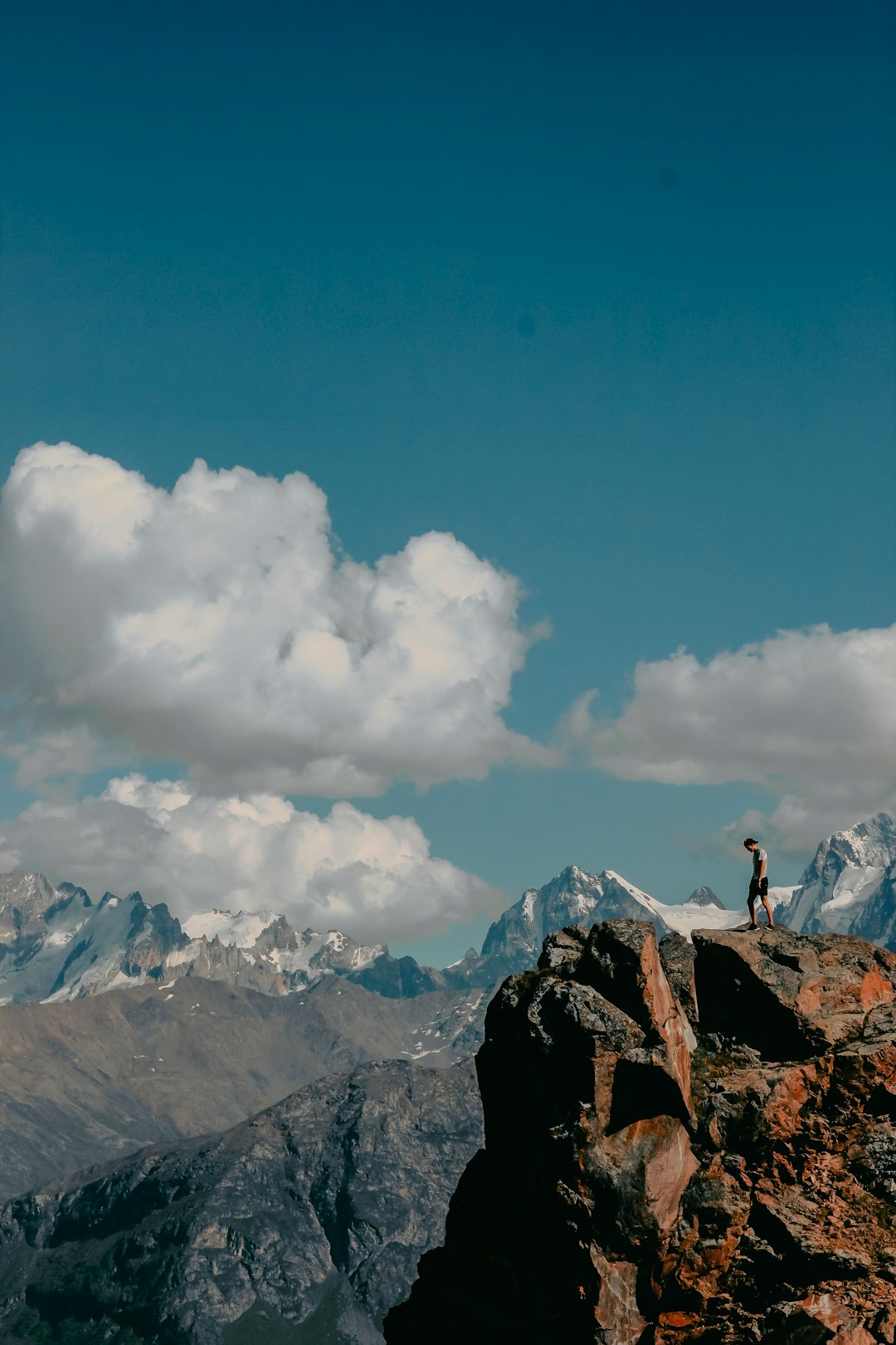 person standing on rock formation under blue sky and white clouds during daytime