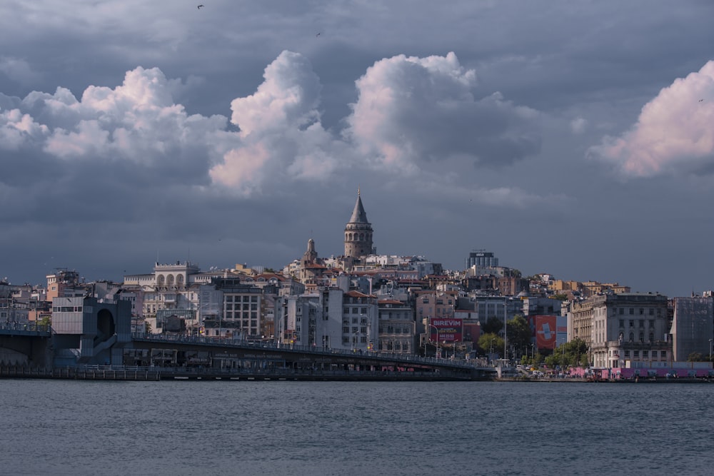 white and brown concrete building near body of water under white clouds and blue sky during