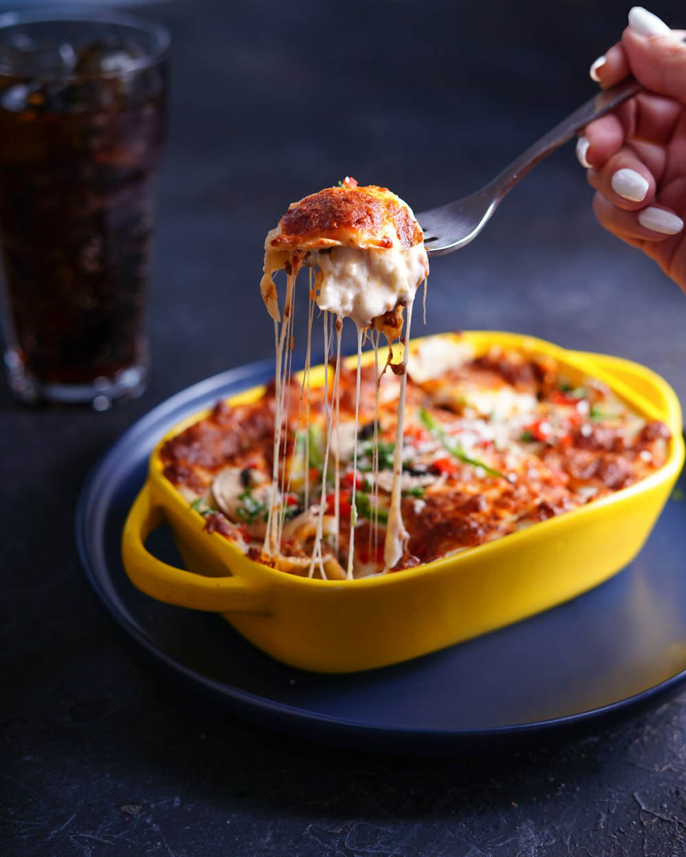 Person mit Edelstahlgabel und gelber Schüssel mit Essen