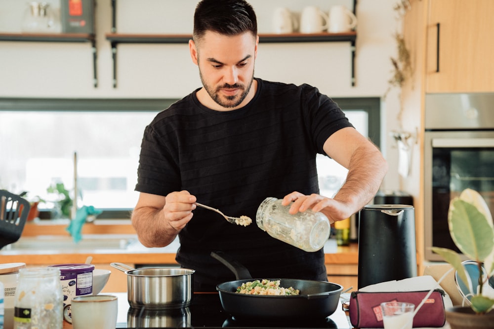 man in black crew neck t-shirt holding stainless steel cooking pot