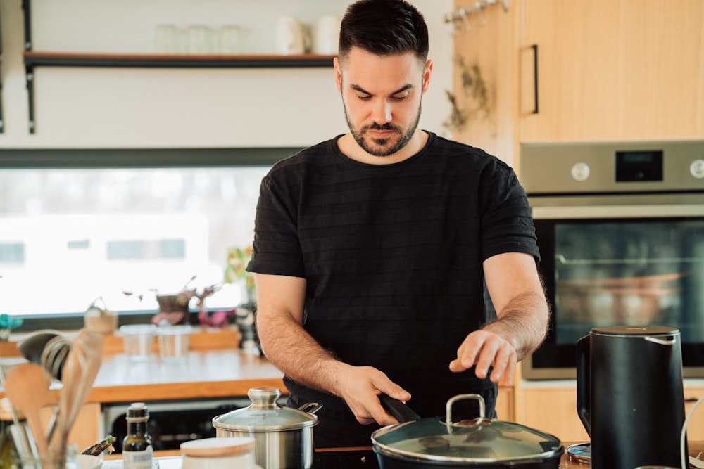 boy in black crew neck t-shirt holding stainless steel cooking pot