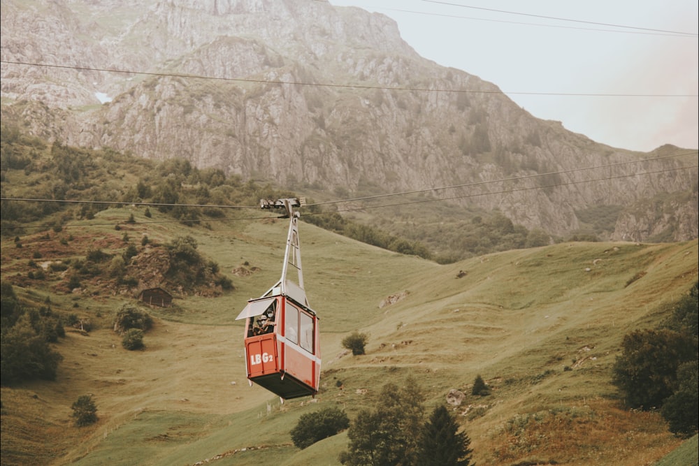 red cable car over green grass field during daytime