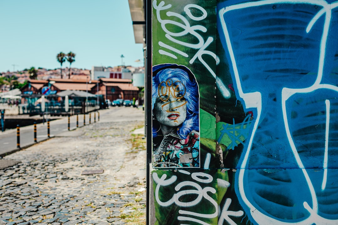 woman in yellow and black floral shirt standing beside blue and white graffiti during daytime