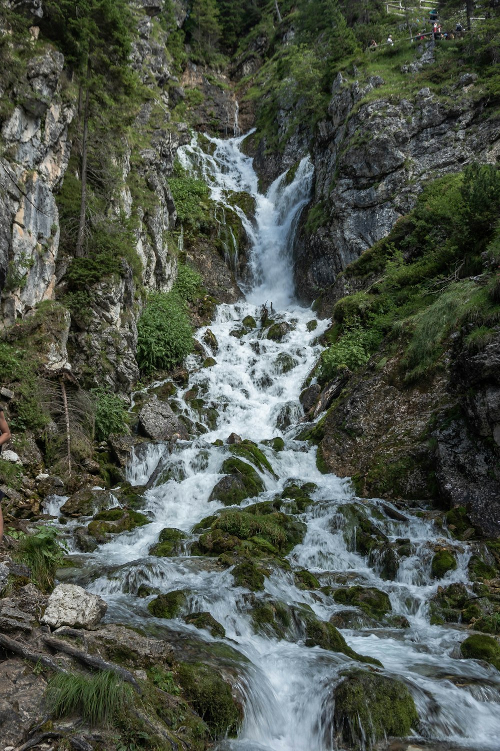 water falls between green and gray rocky mountain during daytime