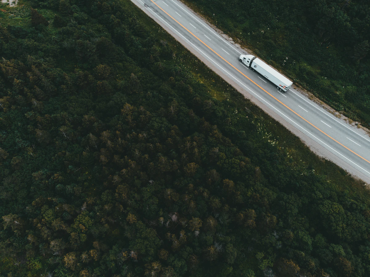 A freight truck travelling along a highway through a green forest