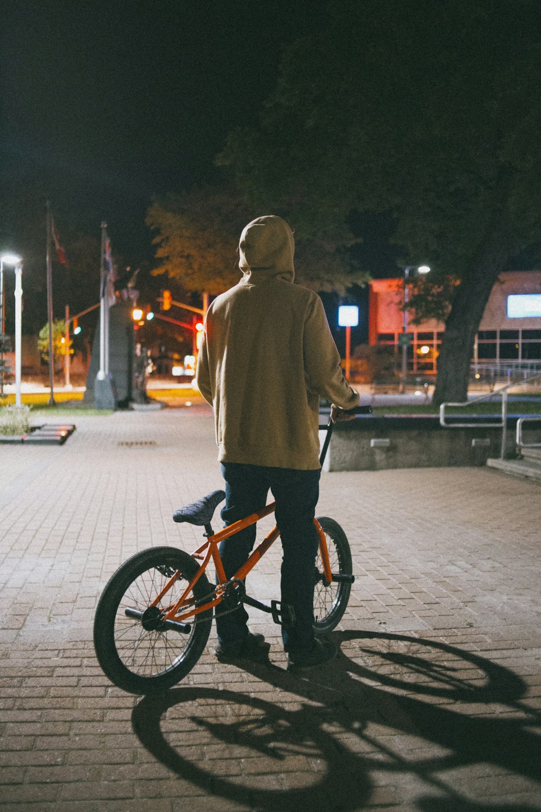 boy in brown hoodie riding on bicycle during daytime