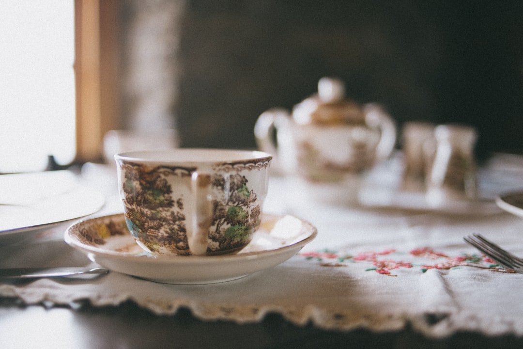 white and green floral ceramic teacup on saucer