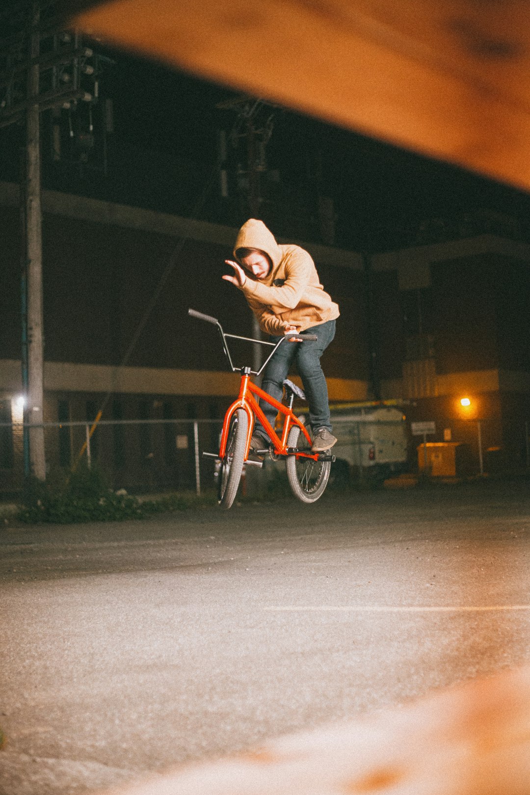 man in brown jacket riding red bicycle on road during night time