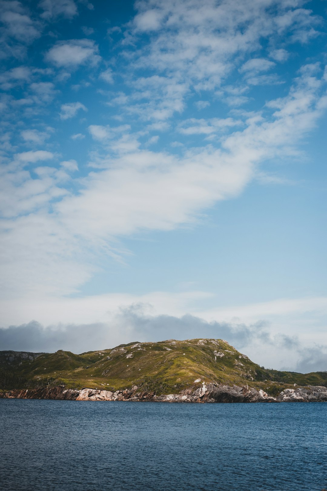 green grass covered mountain under white clouds during daytime