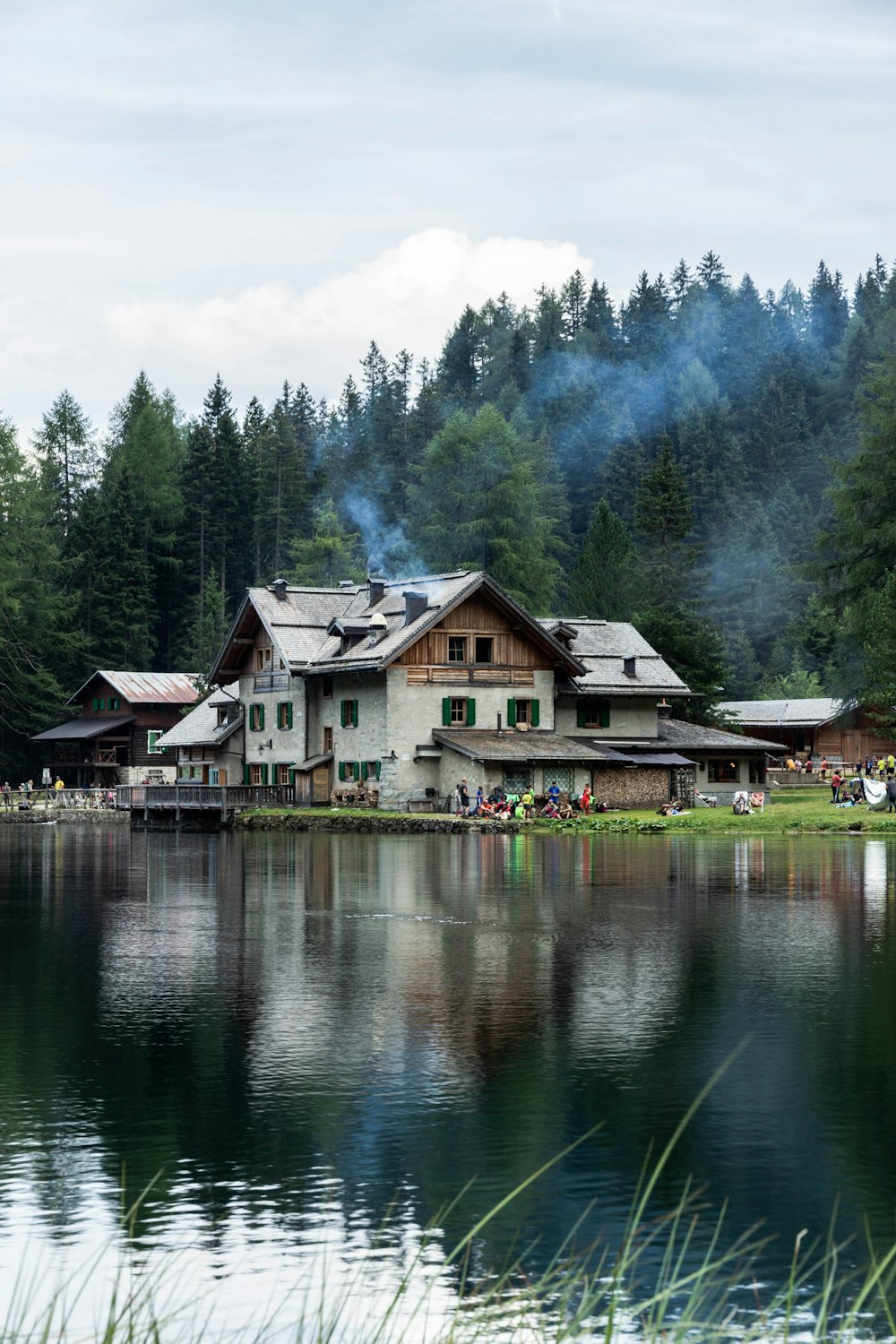 brown and white house near green trees and lake during daytime