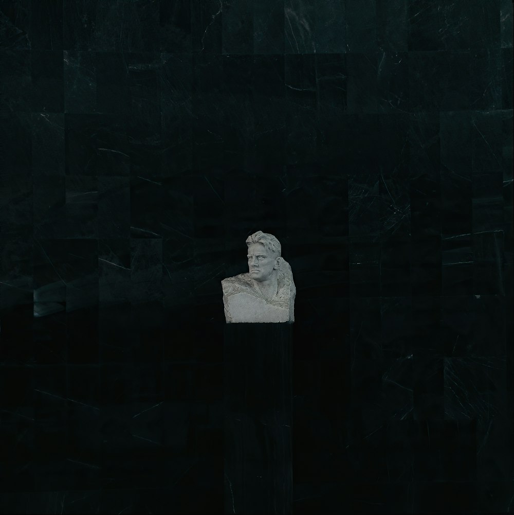 person in white hoodie standing in front of black brick wall