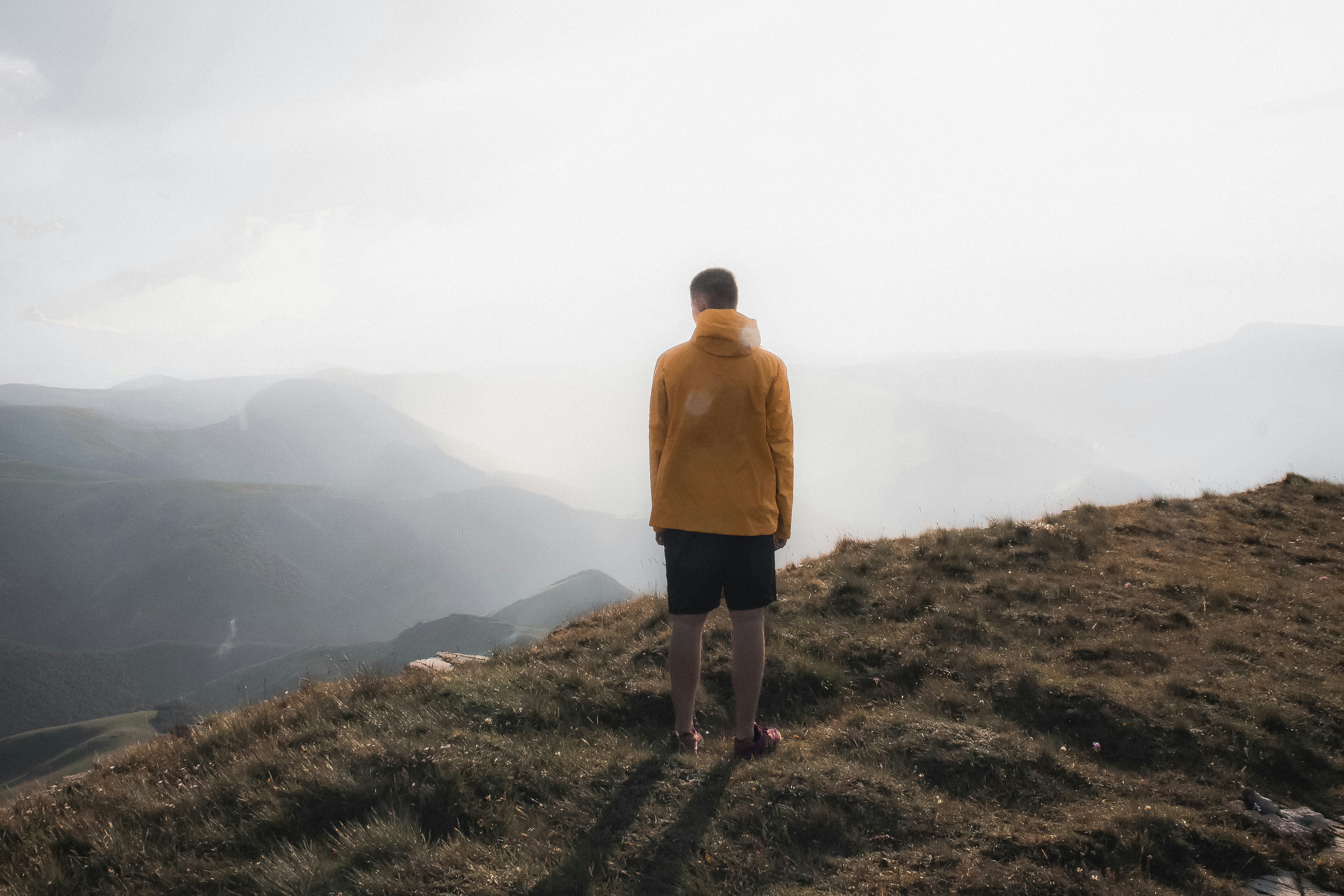 man in yellow hoodie standing on green grass field during daytime