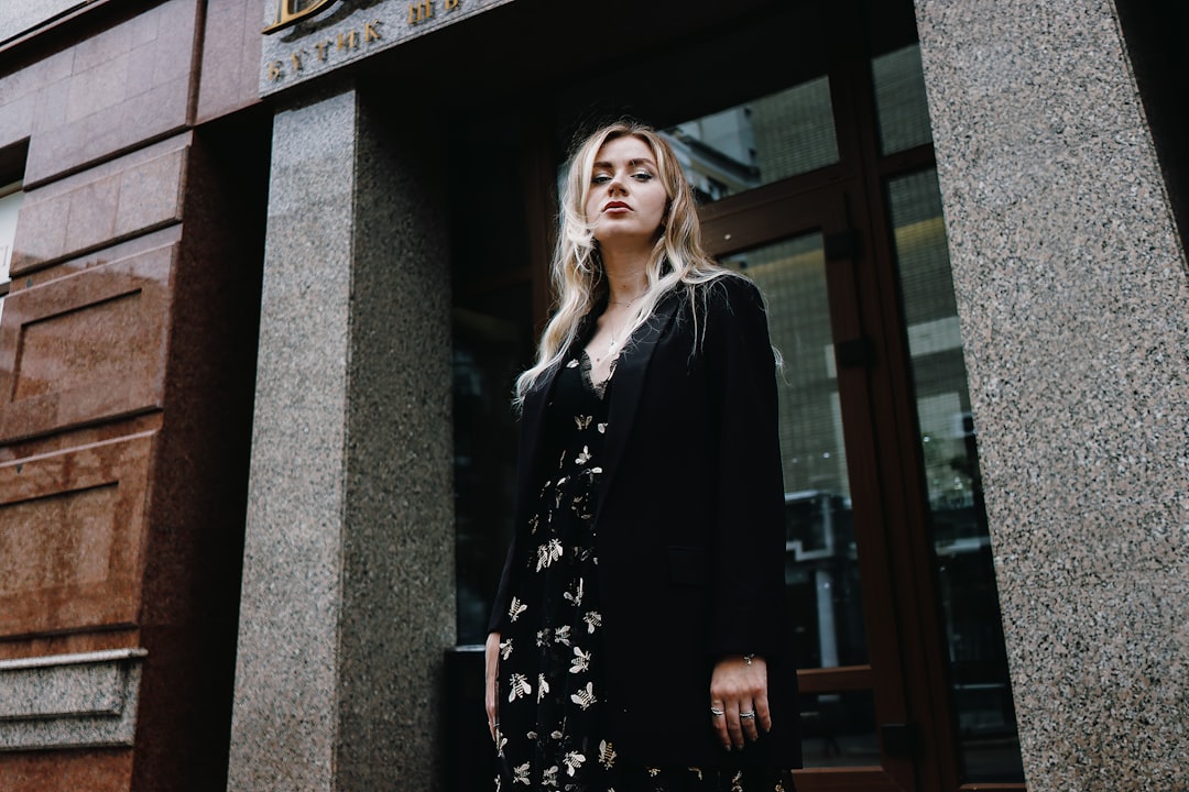 woman in black and white floral long sleeve dress standing beside brown wooden framed glass window