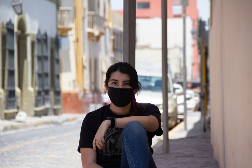 man in black crew neck t-shirt wearing black sunglasses sitting on concrete bench during daytime