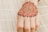 A henna design is intricately drawn on the back of a hand, showcasing detailed patterns with floral and circular motifs. The hand rests on a bamboo mat, providing a textured background.