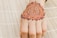 A henna design is intricately drawn on the back of a hand, showcasing detailed patterns with floral and circular motifs. The hand rests on a bamboo mat, providing a textured background.