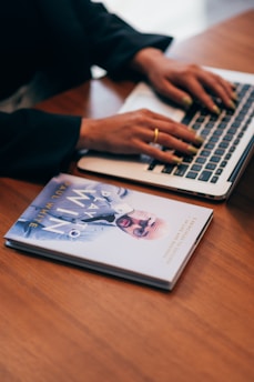 person using macbook pro on brown wooden table