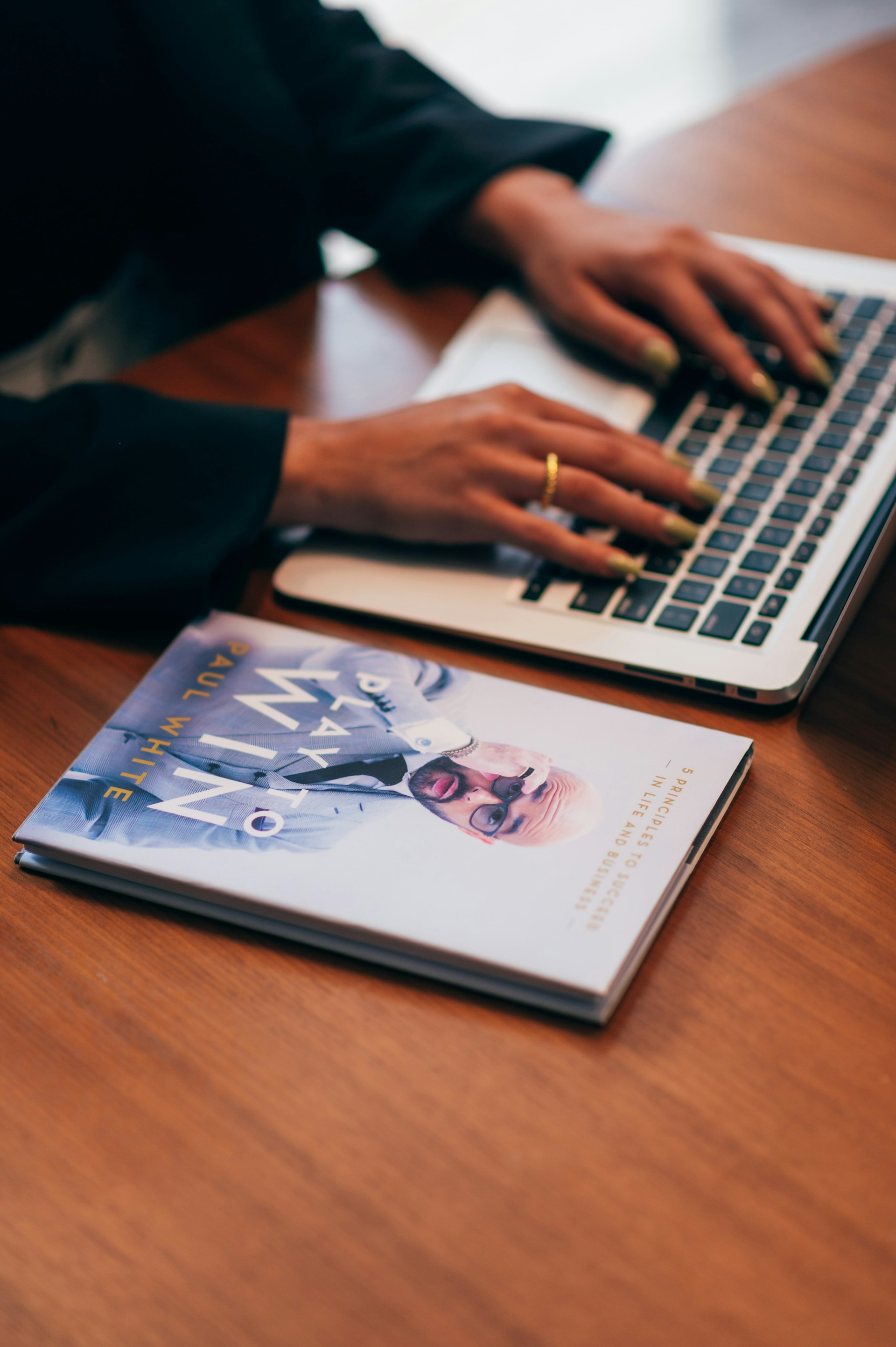 person using macbook pro on brown wooden table