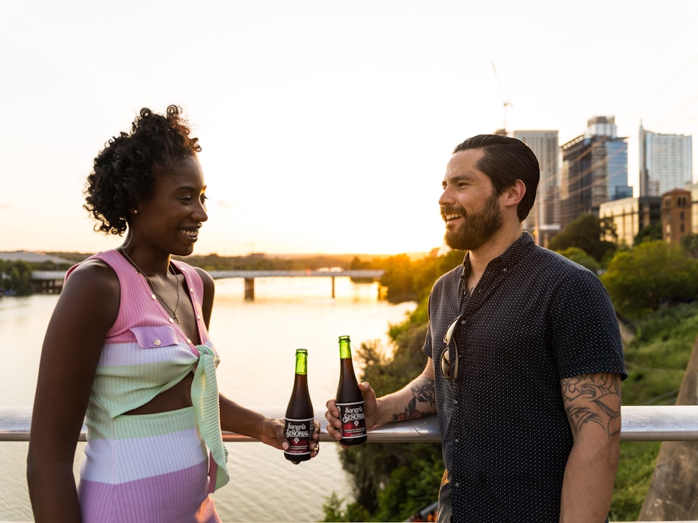 man in blue dress shirt holding bottle beside woman in pink dress