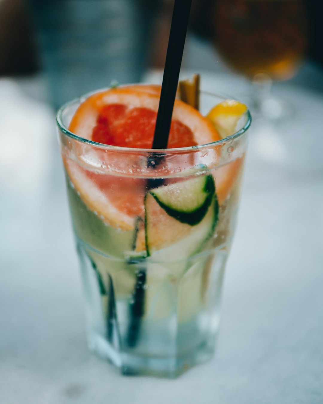 clear drinking glass with orange and black straw