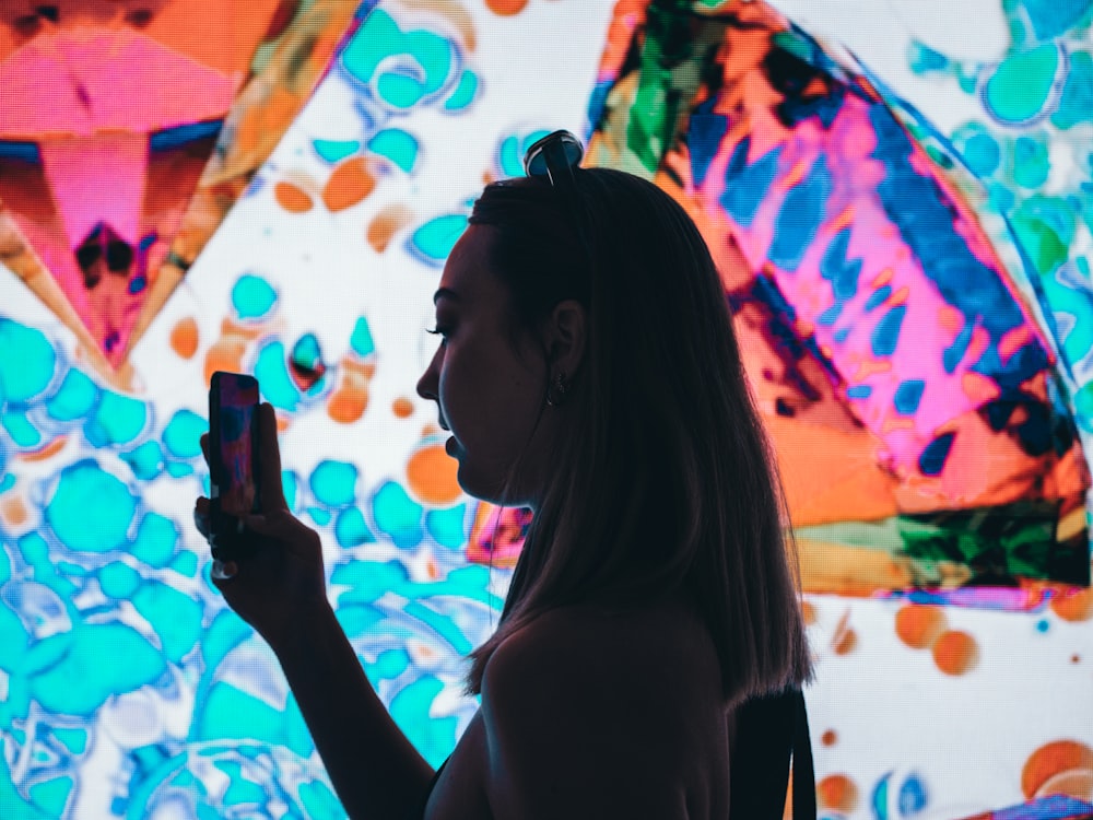 woman in black tank top holding a black smartphone