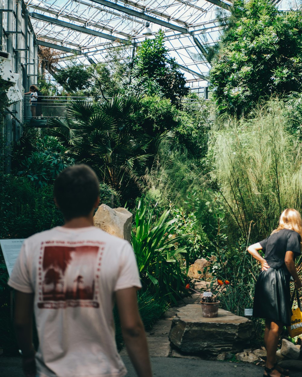 man in white t-shirt standing near green plants during daytime