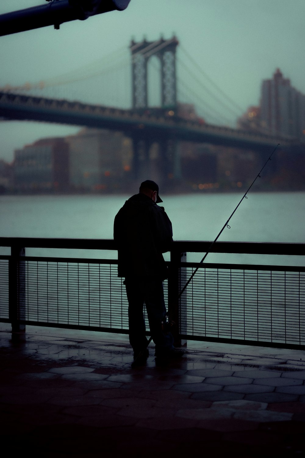 昼間、橋の上に立つ黒いジャケットの男