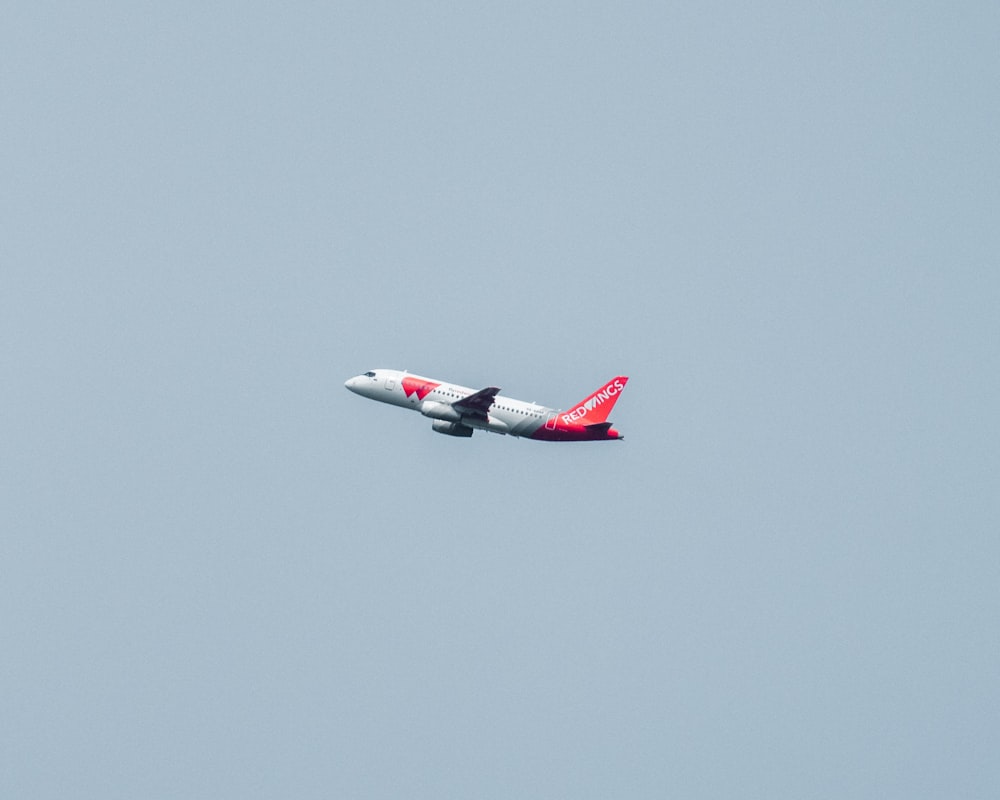 white and red airplane flying in the sky