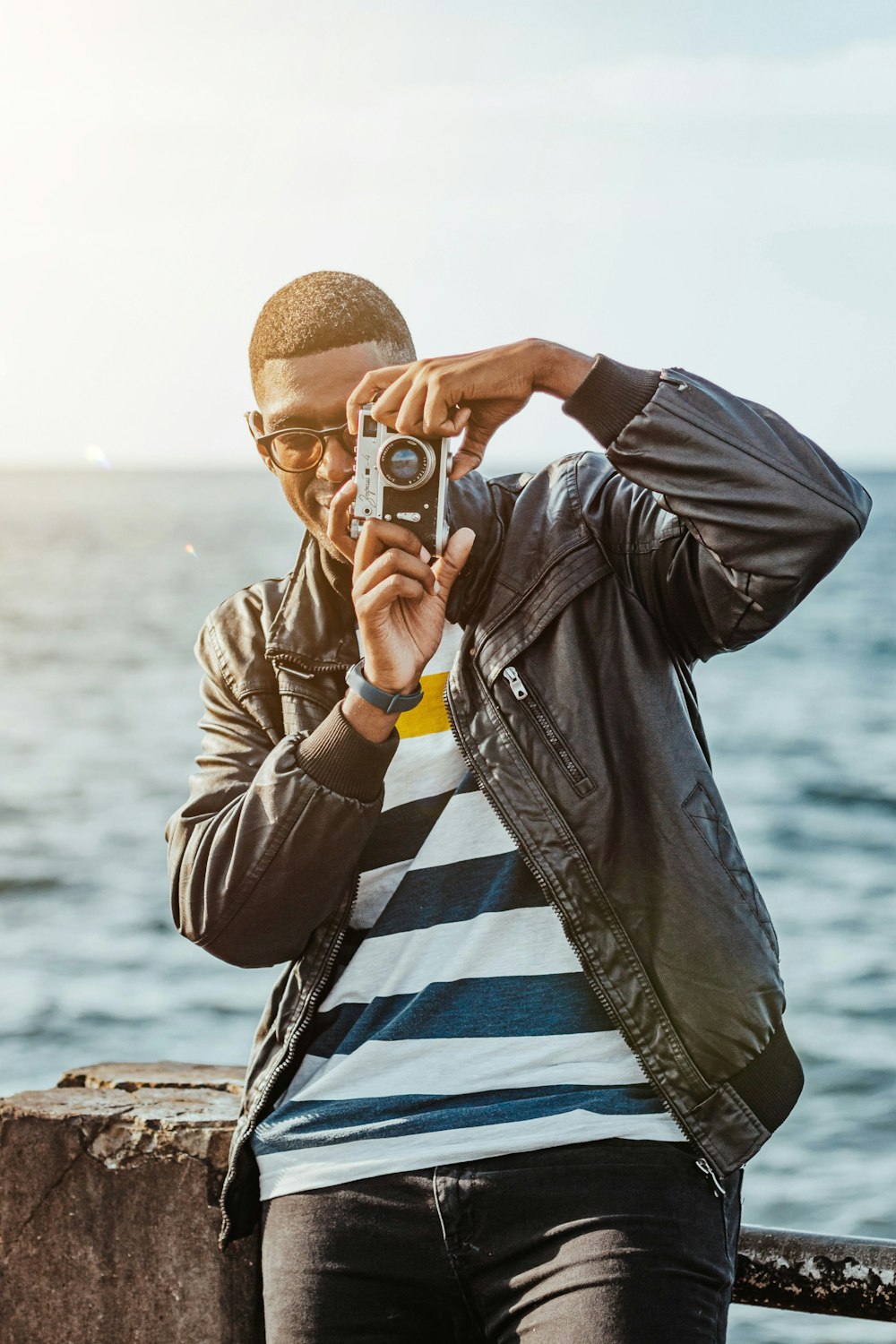 man in black leather jacket holding black smartphone