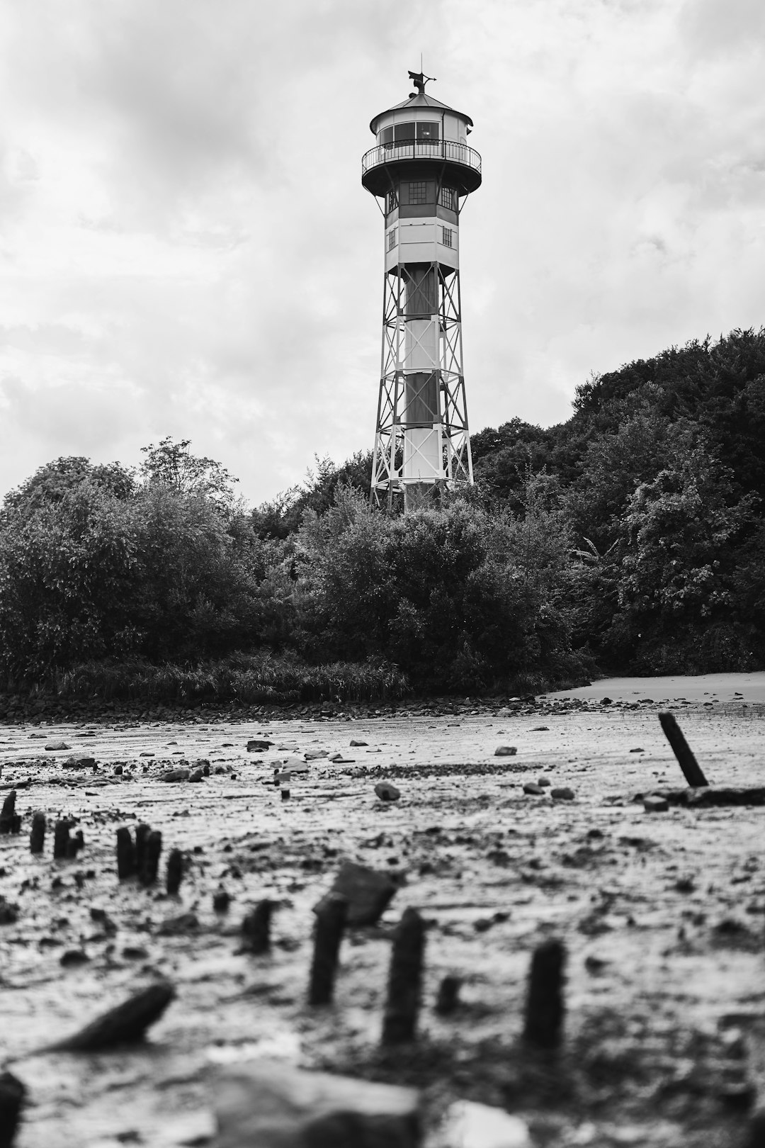 grayscale photo of people walking near lighthouse