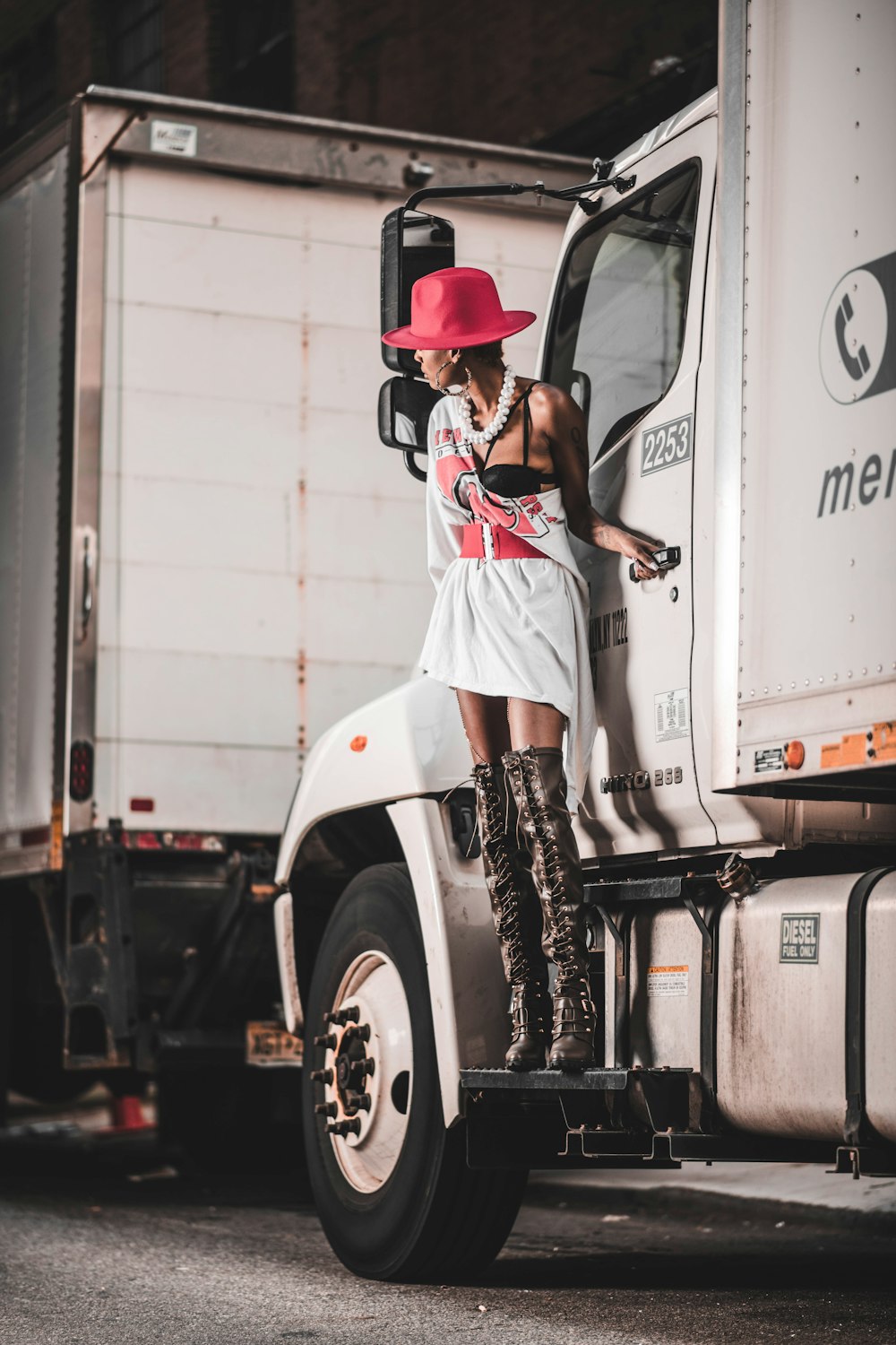 woman in white and red t-shirt and red hat standing beside white truck during daytime