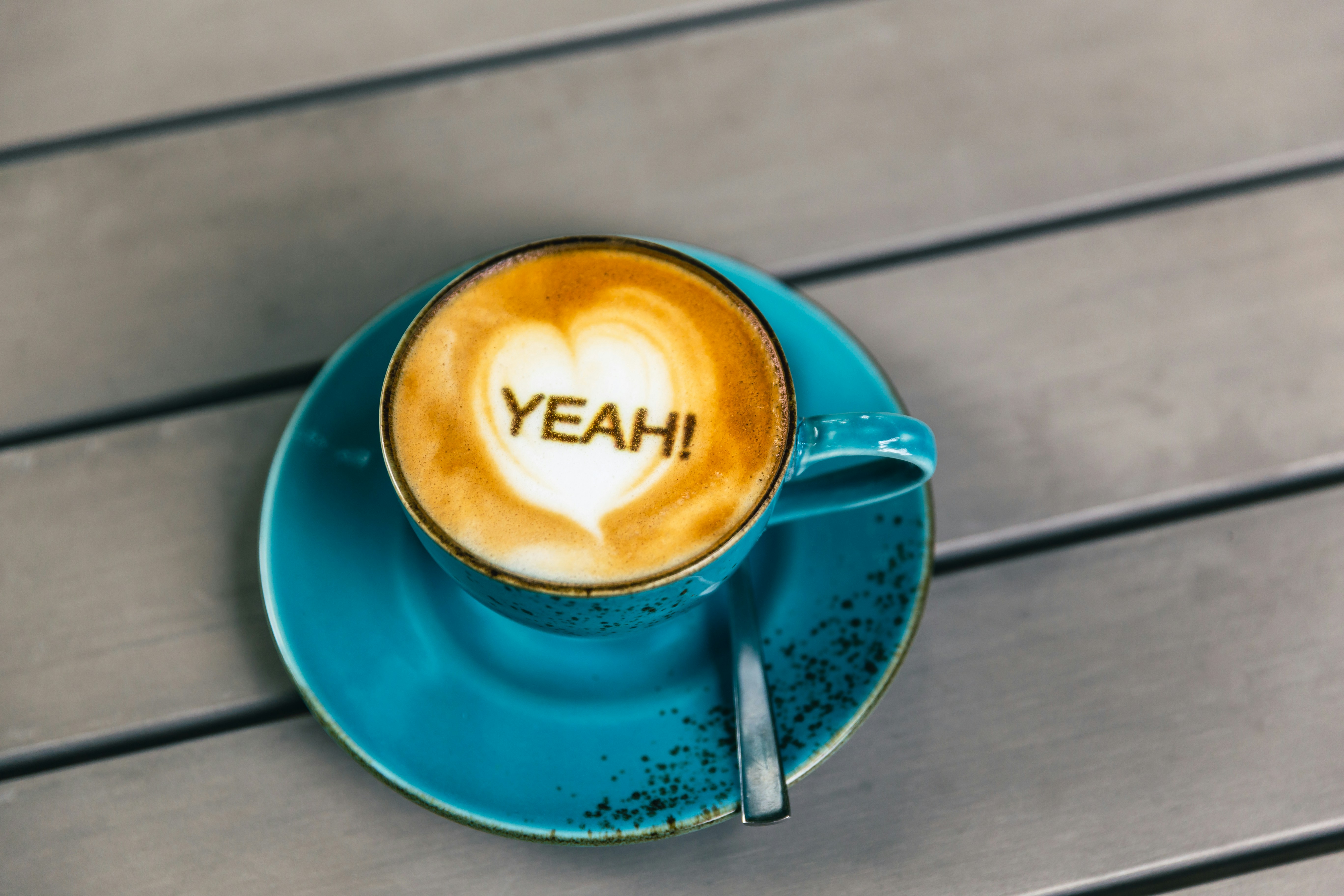 Communication by coffee. One cup of freshly brewed coffee (cappuccino) on a table, with the following text on the coffee foam: 