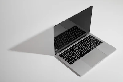 A slim, high-performance laptop open on a minimalist desk with a slate-colored background.