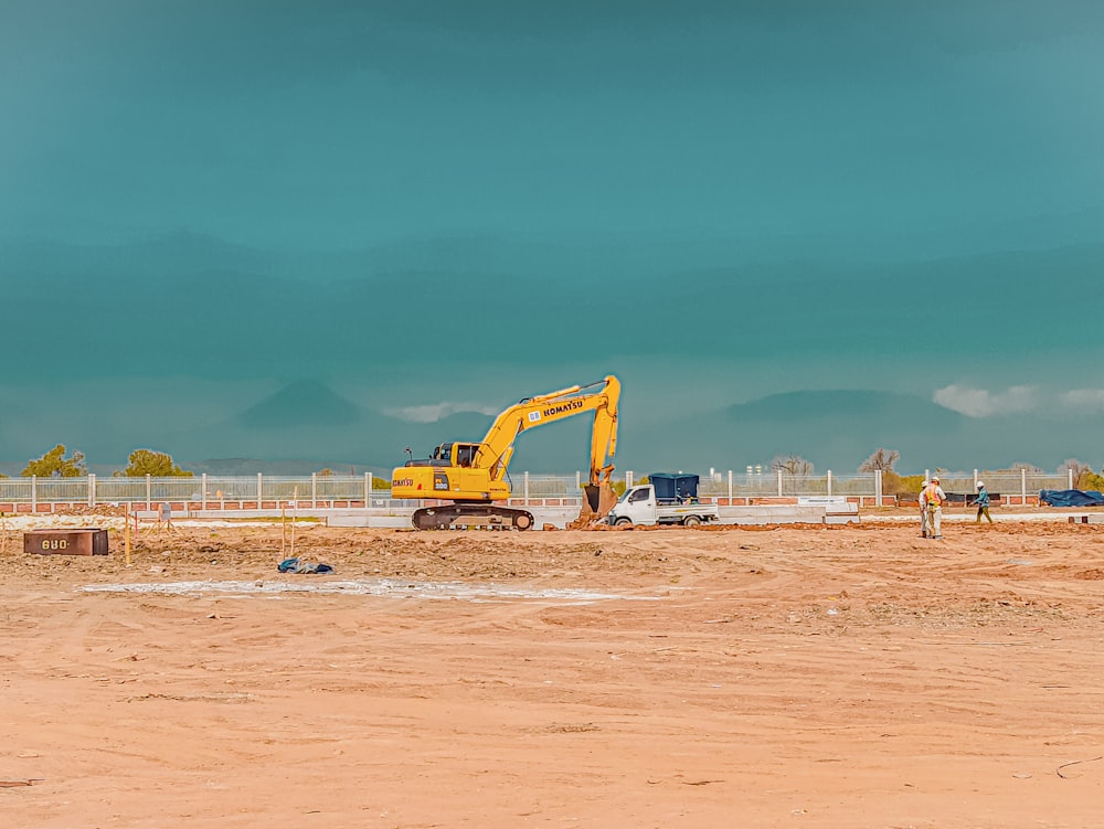 excavadora amarilla sobre arena marrón bajo un cielo azul durante el día