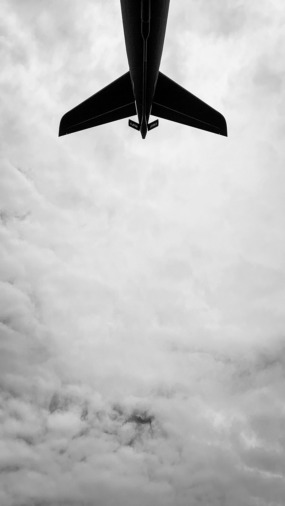 black and white plane under white clouds during daytime