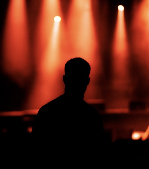 silhouette of man standing in front of stage lights