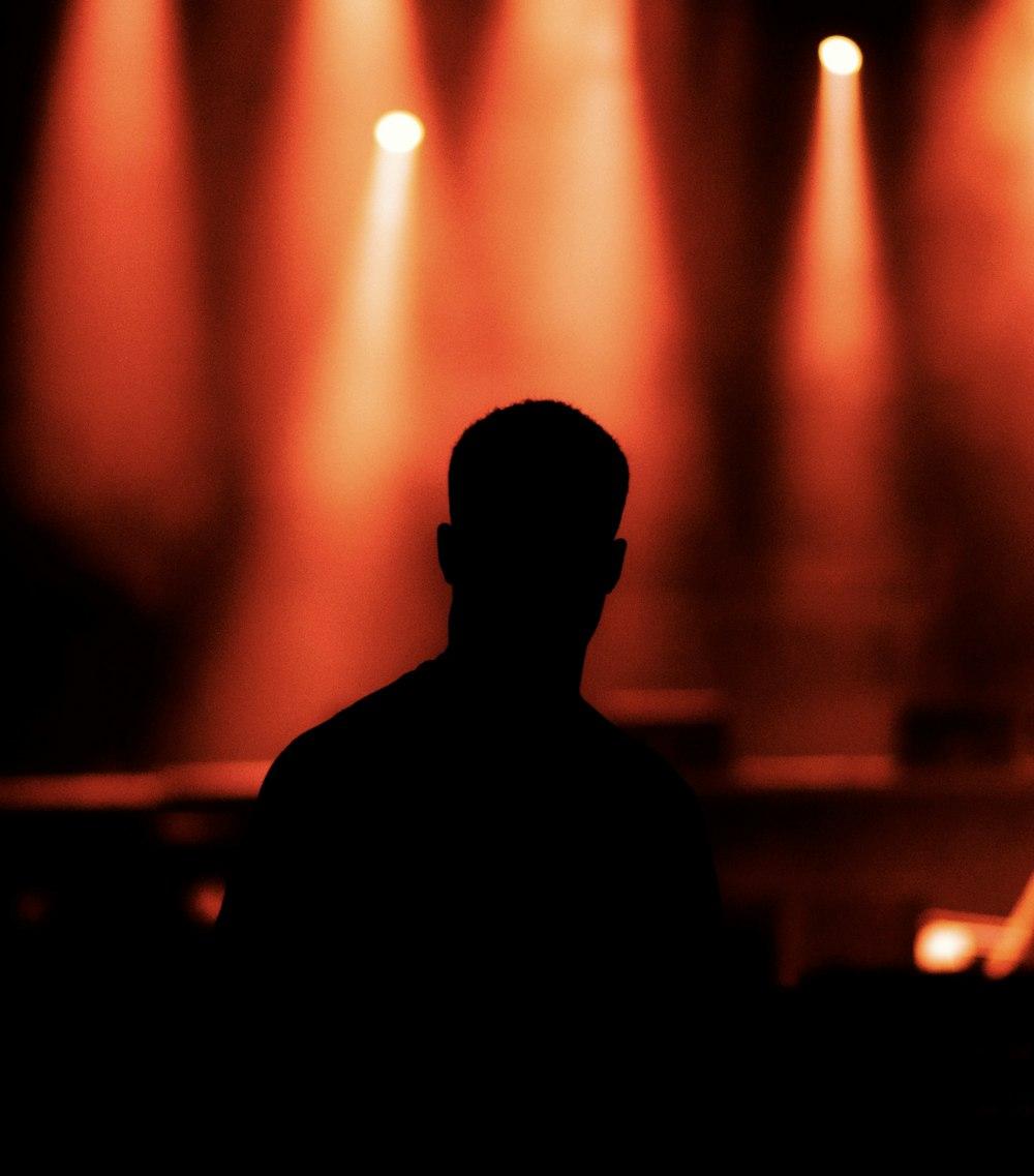 silhueta do homem em pé na frente das luzes do palco