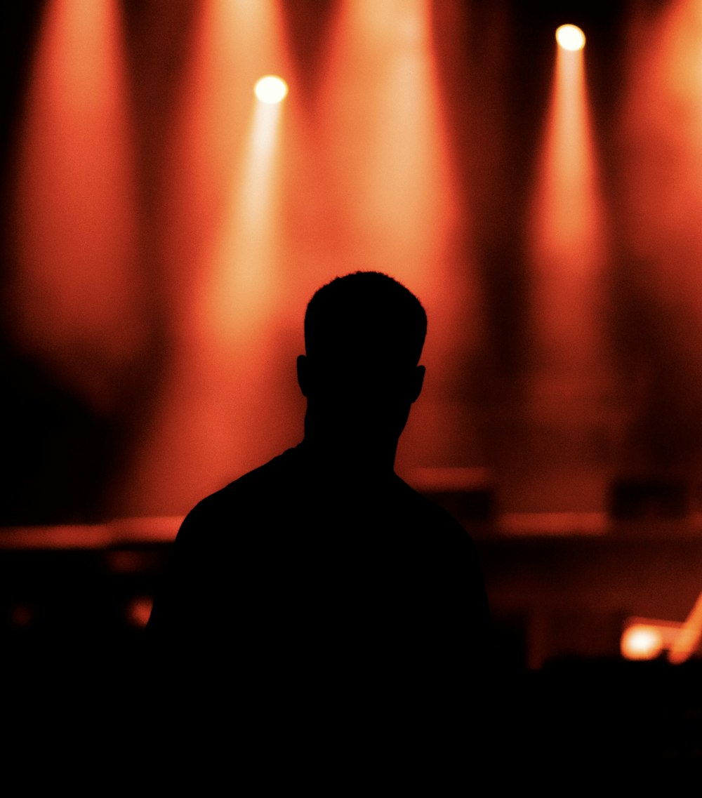 silhouette of man standing in front of stage lights
