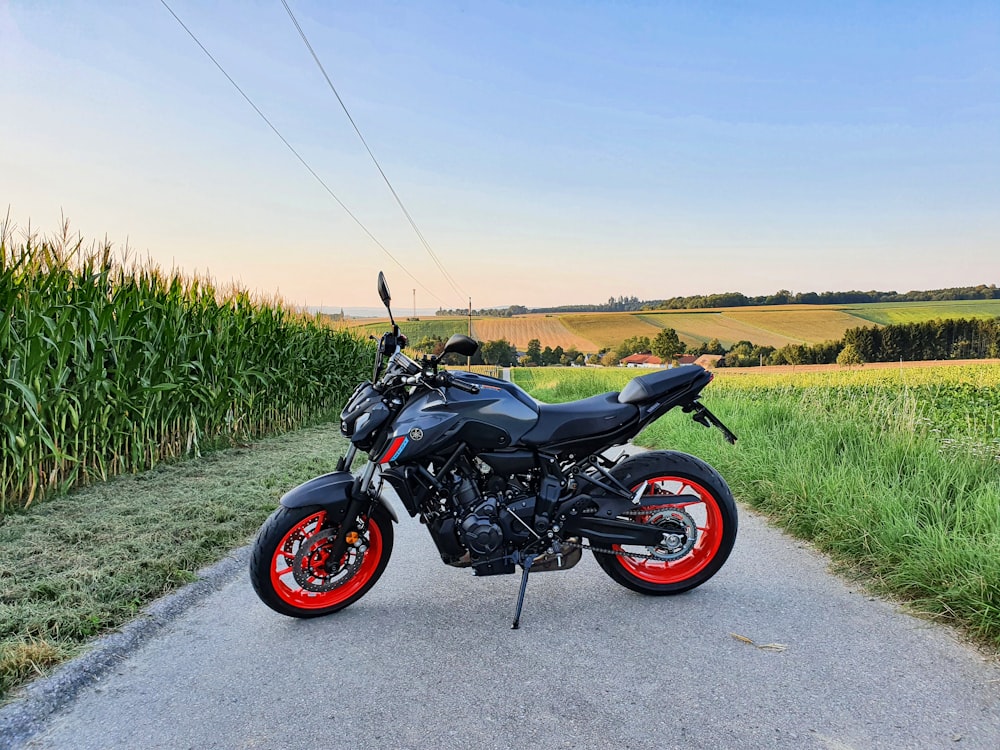 schwarz-rotes nacktes Motorrad, tagsüber auf grauer Asphaltstraße geparkt