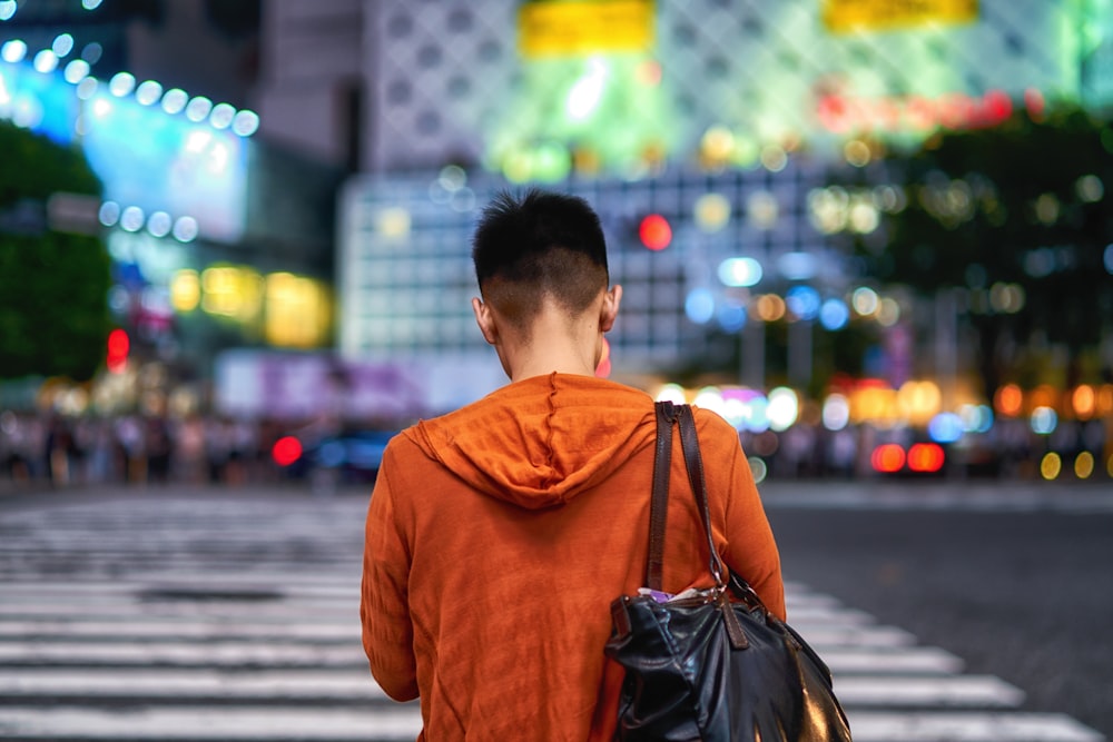 man in brown hoodie carrying black leather backpack